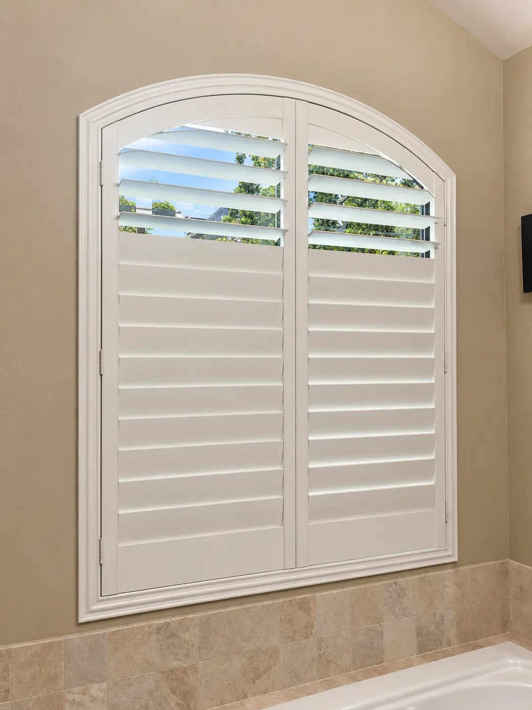Custom white shutters fitted to an eyebrow arch window